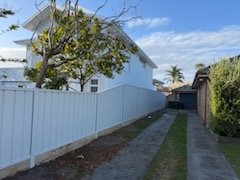 White Colorbond fence along a side path